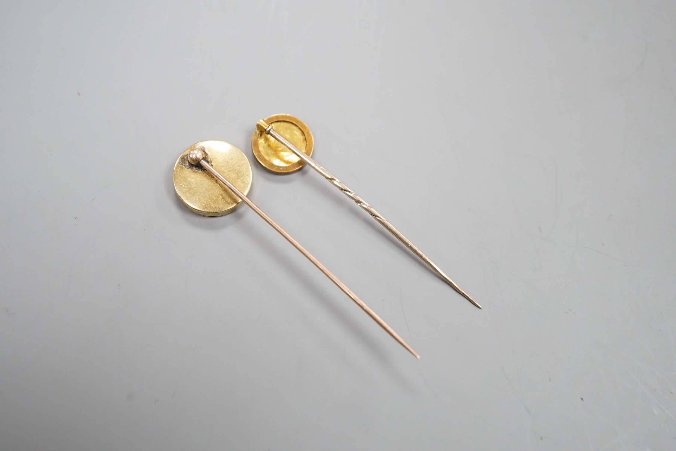Two early 20th century yellow metal and enamel stick pins, both decorated with the head of a dog, largest, 70mm, gross weight 7.6 grams.